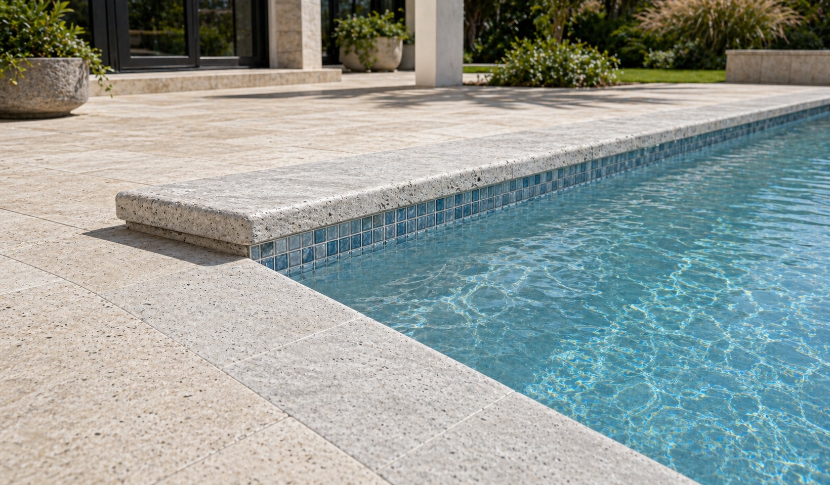 Silver travertine coping paired with pale decking and blue waterline tile