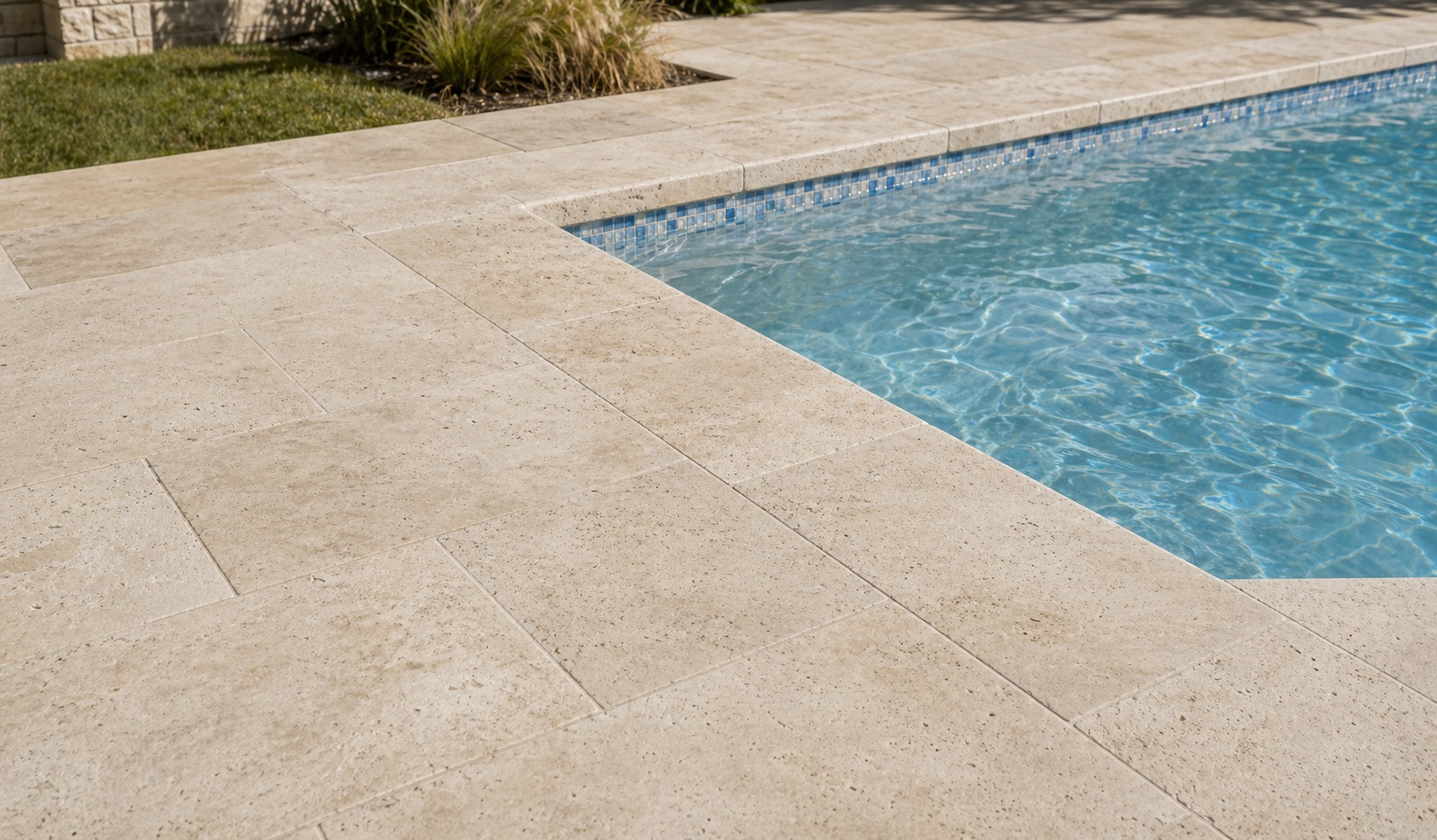 Wide view of a travertine pool deck meeting matching coping and waterline tile